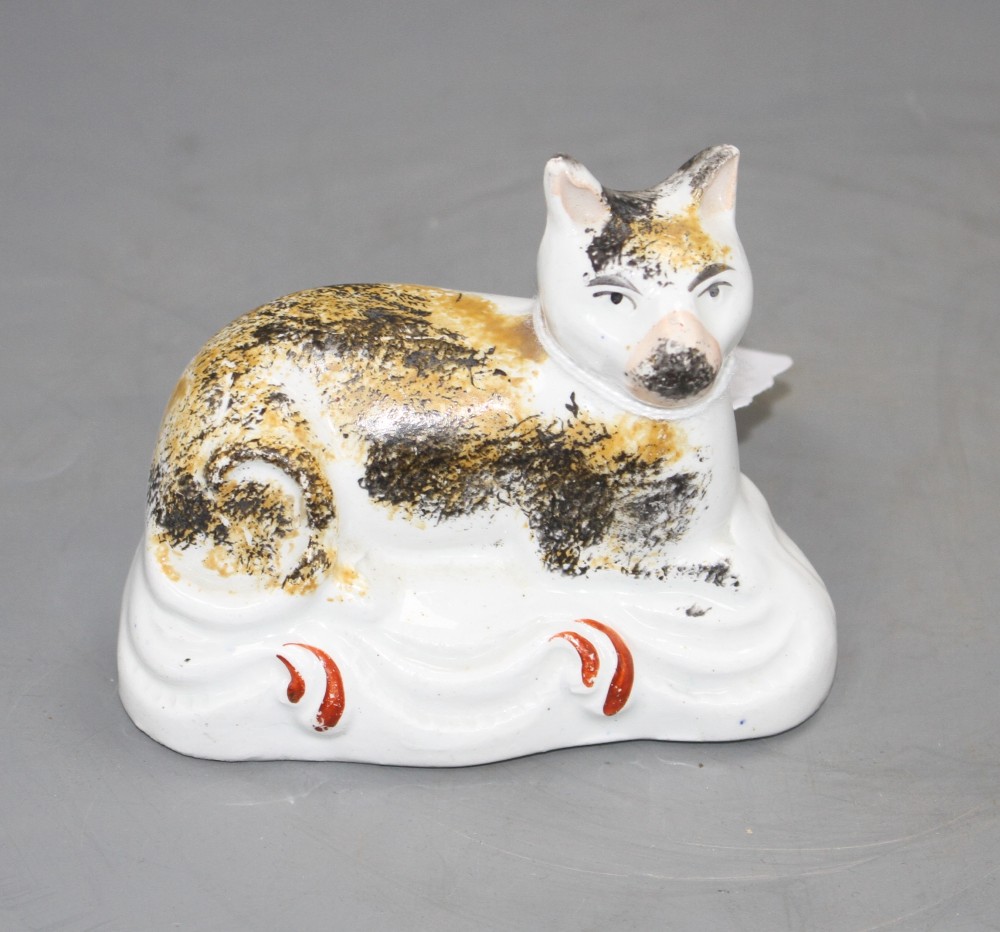 A Staffordshire porcelaneous flatback figure of a recumbent cat, mid 19th century, L. 9cm